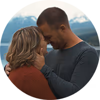 Thomas and Sadie forehead to forehead with Montana mountains and water behind them